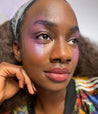 Model with dark skin tone wearing Colorwand in glabra smudged along outer eyes and cheekbones.