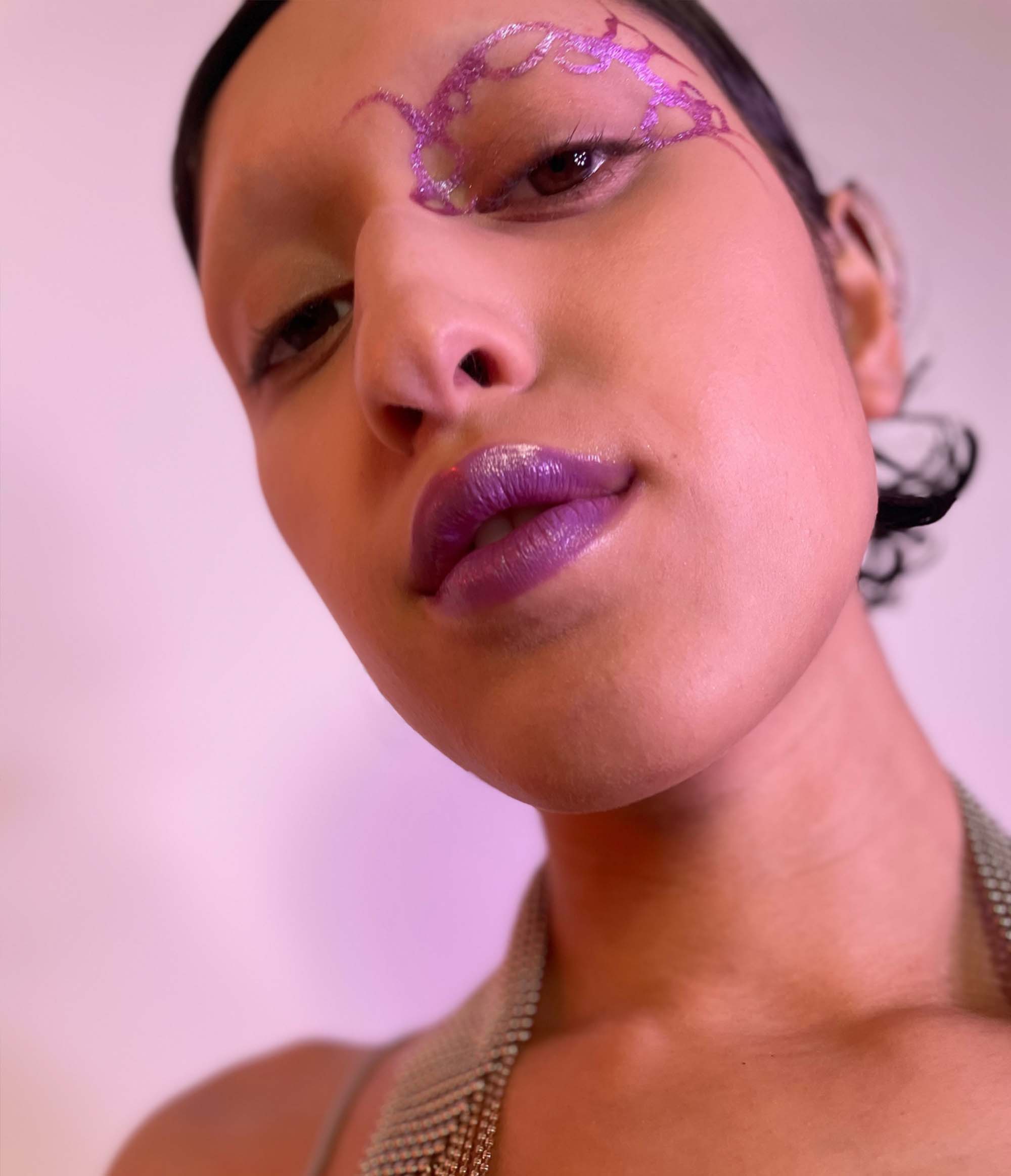 Model with medium tone skin wearing Colorwand in glabra along their left inner nose and brows and on their lips.