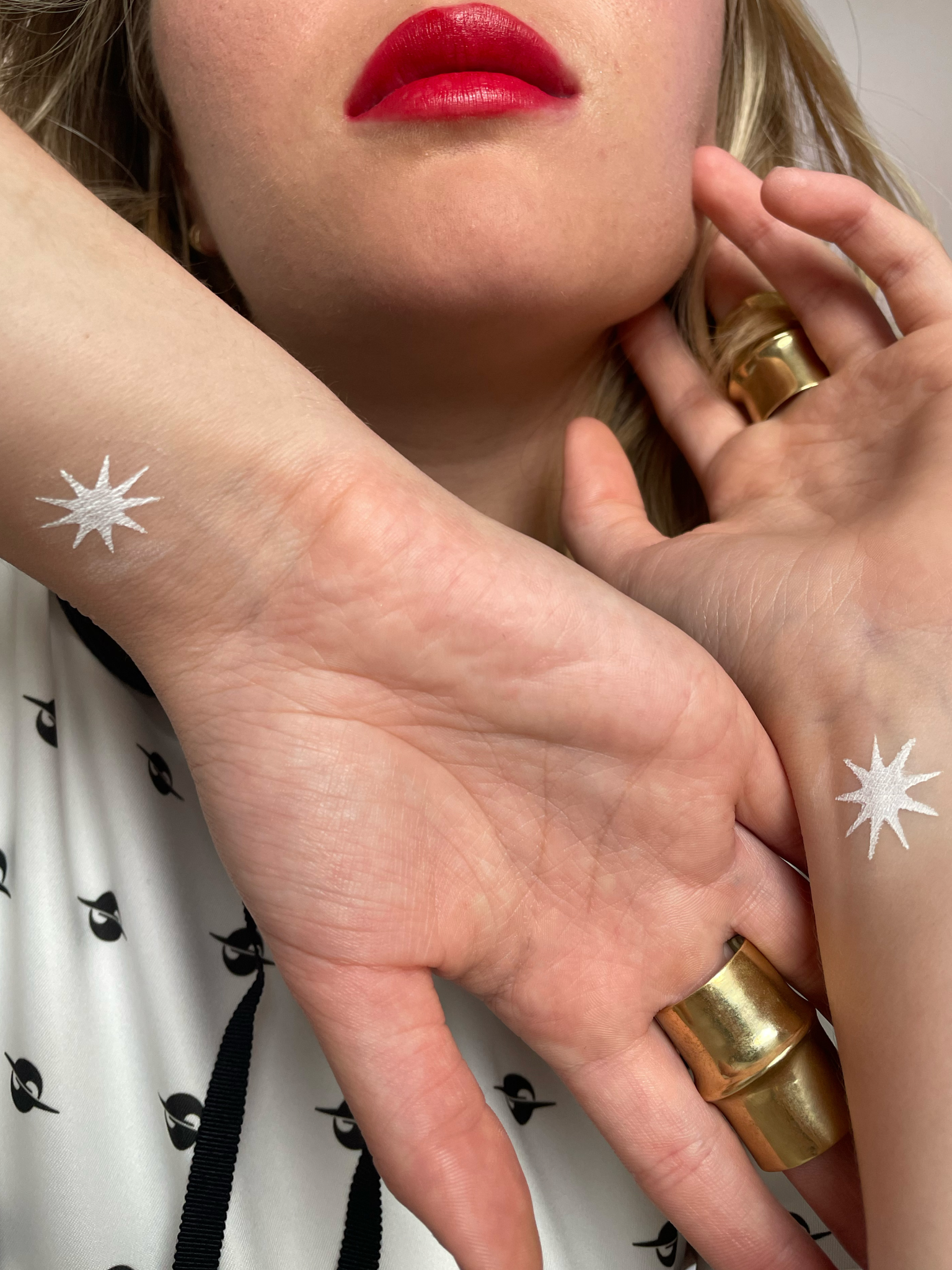 Model with medium skin tone wearing a deepdive colorpot in Matilija in starburst shapes on their inner wrists.