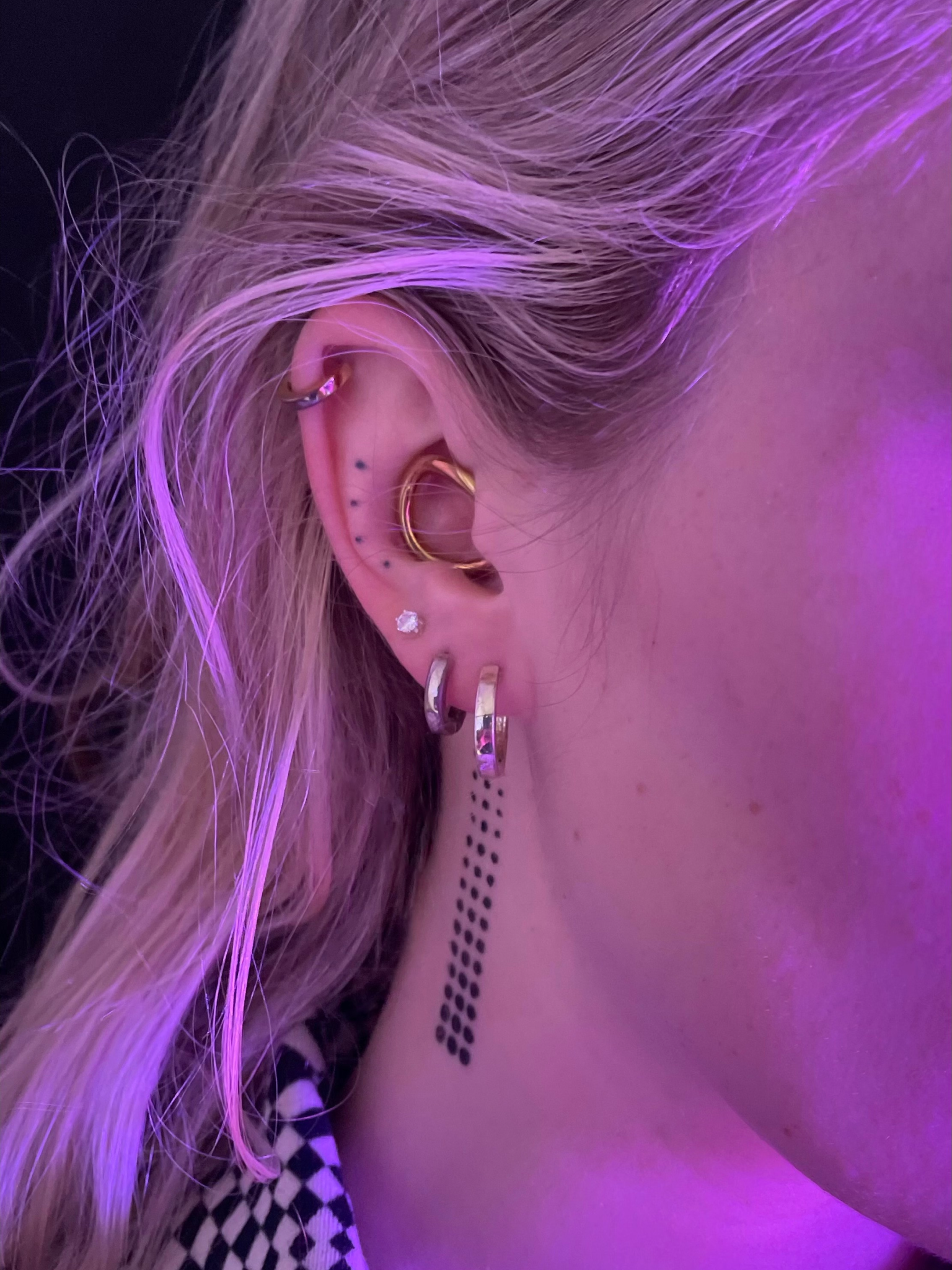 Side view of a model with light skin wearing Deepdive colorpot in Corvid in a dot pattern along the side of their neck.