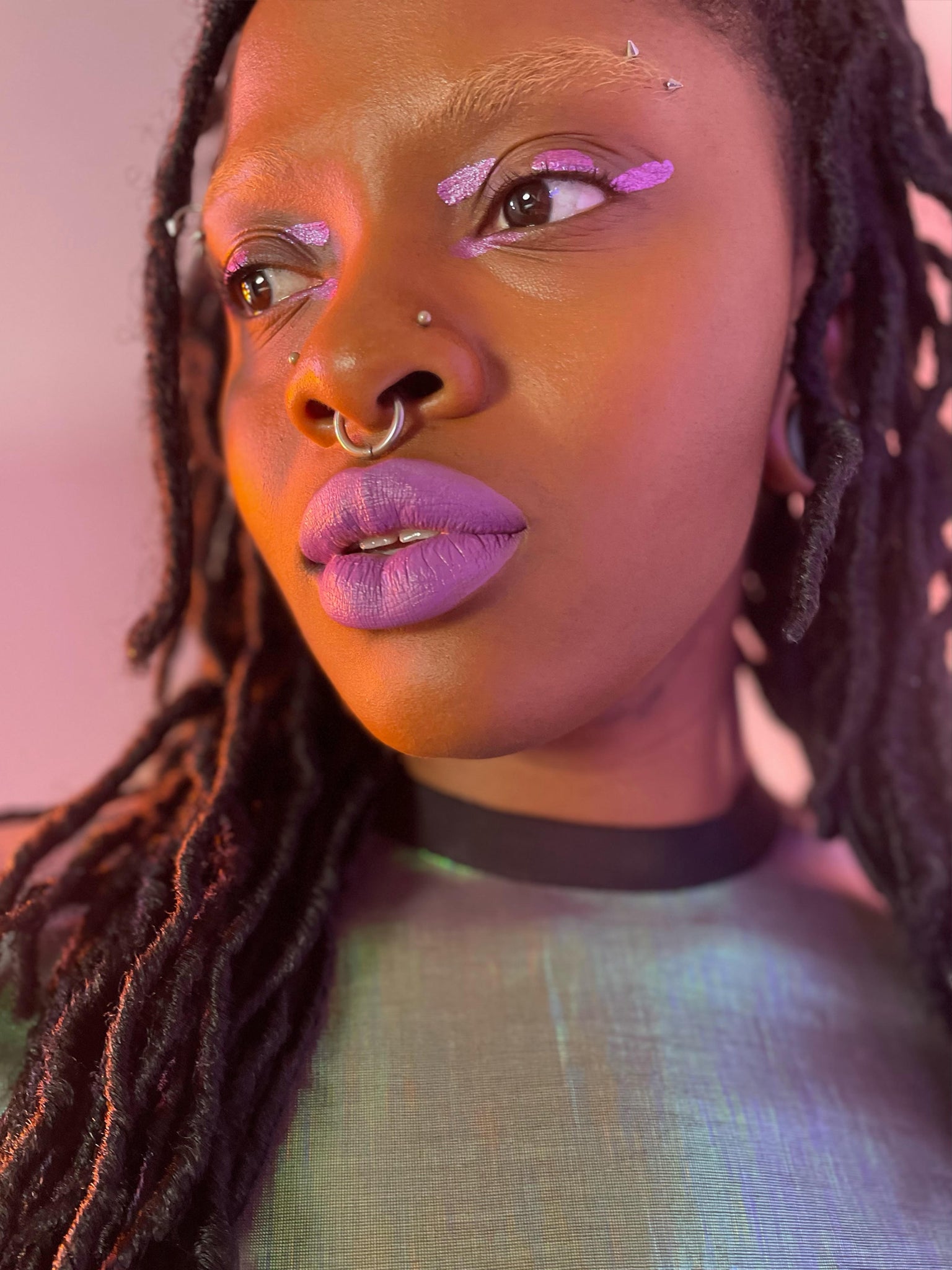 Model with dark skin tone wearing colorwand glabra on their eyelids and lips.