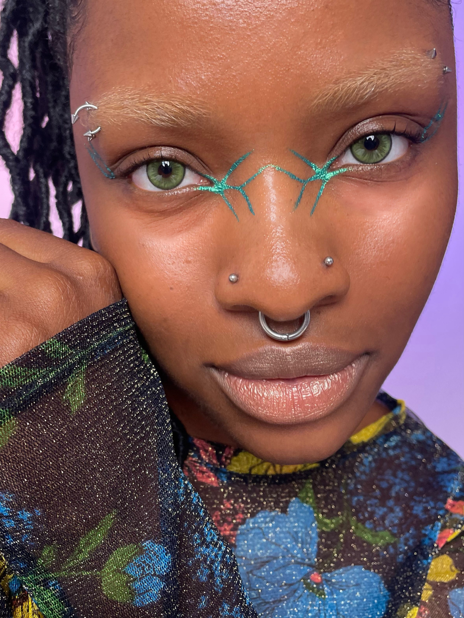 Model with dark skin tone wearing a colorwand in figeater along the bridge of their nose.