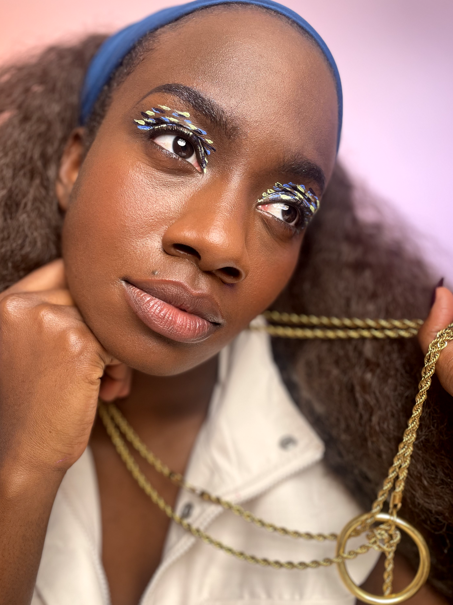 Model with dark skin tone wearing smeared dott patterns on eyelids in blue and white.