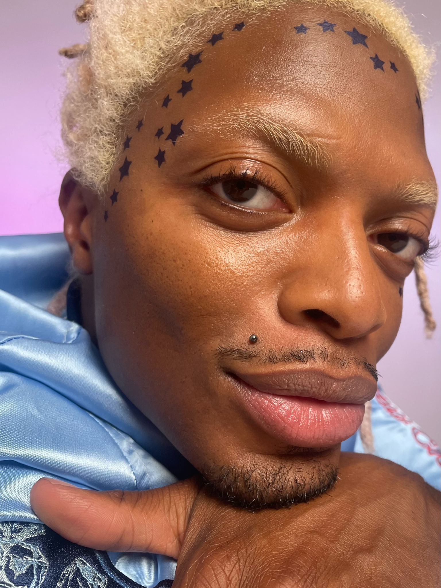 Side view of a Model with dark skin tone wearing star pattern in Corvid along upper forehead and temple.