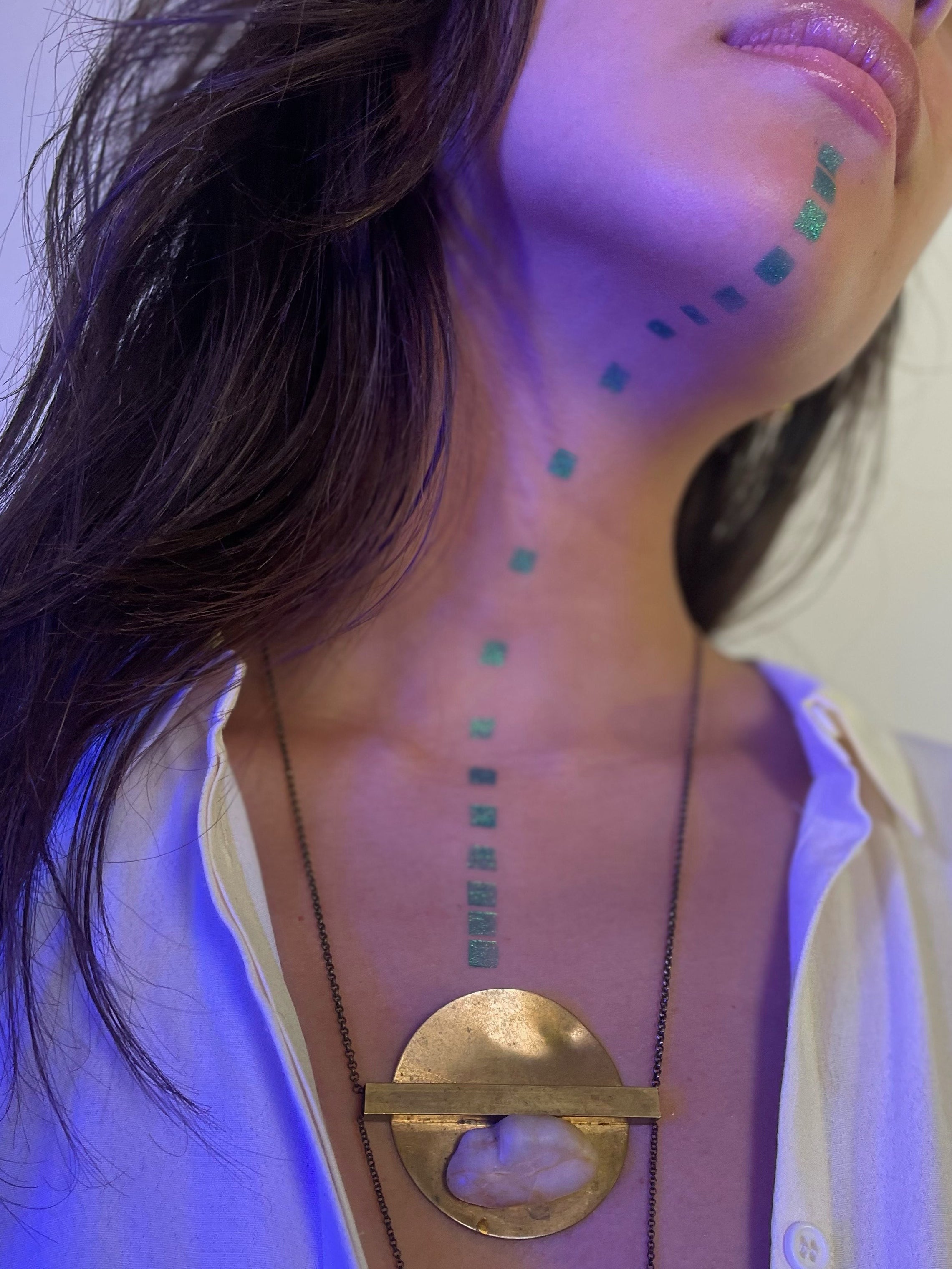 Model wearing Colorwand in figeater in a pattern of squares from their chin along their neck to their chest.