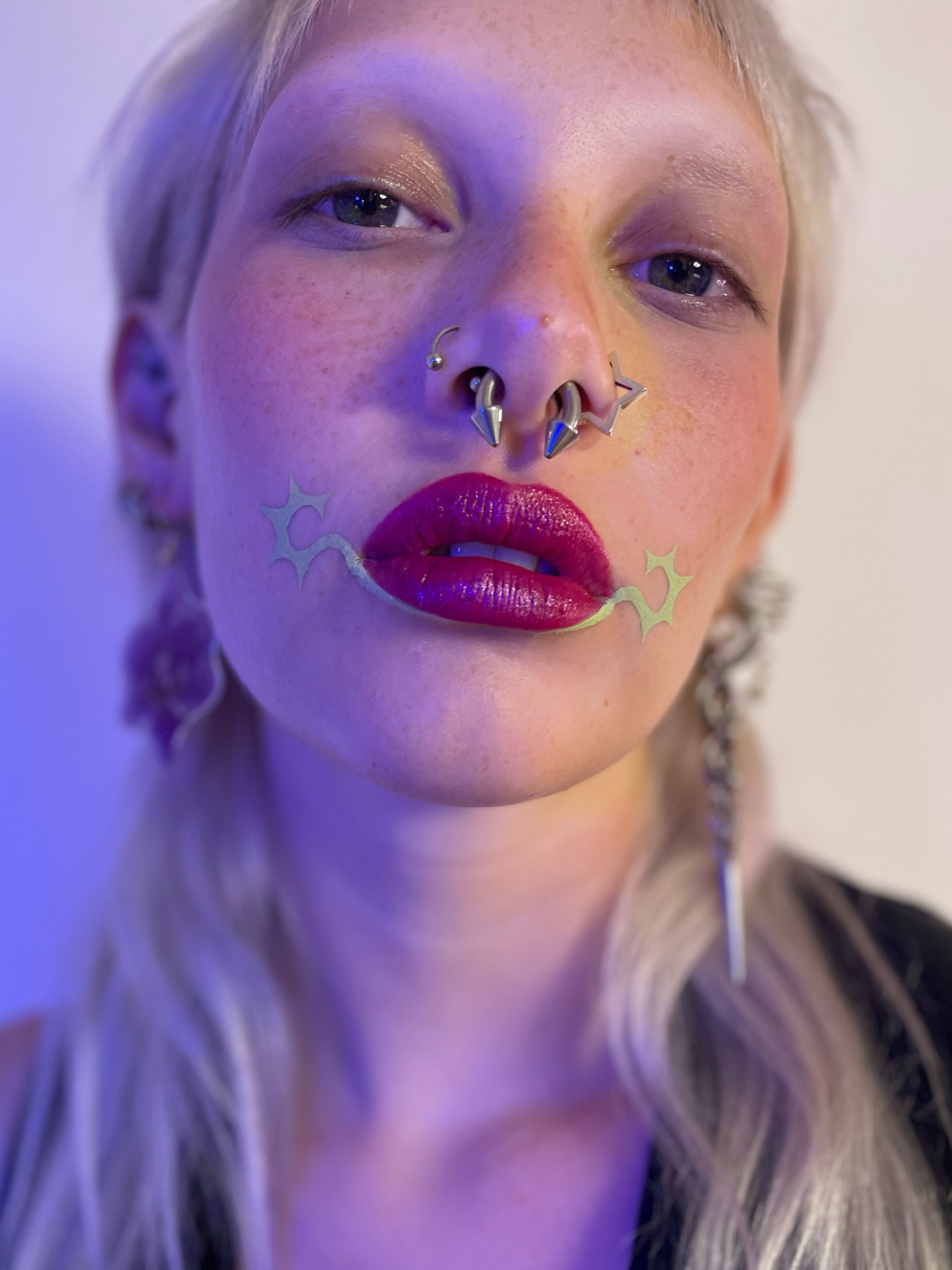 Model with a light skin tone wearing Deepdive colorpot in Sagebrush under their bottom lip with starbursts at the corners of their mouth.