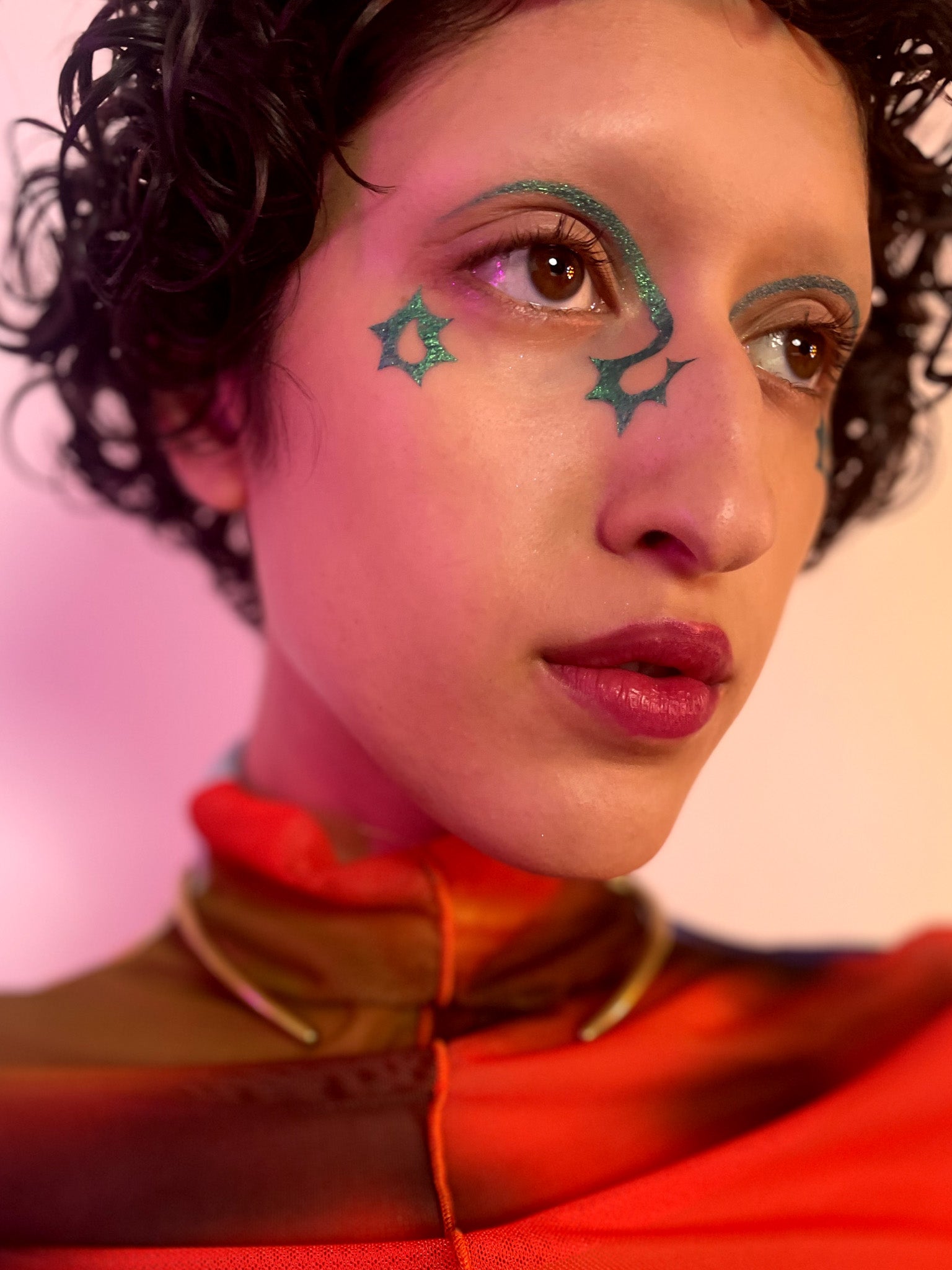 Model with medium skin tone wearing figeater in an arch under their brow with a star on the inner and outer corners of their eyes.