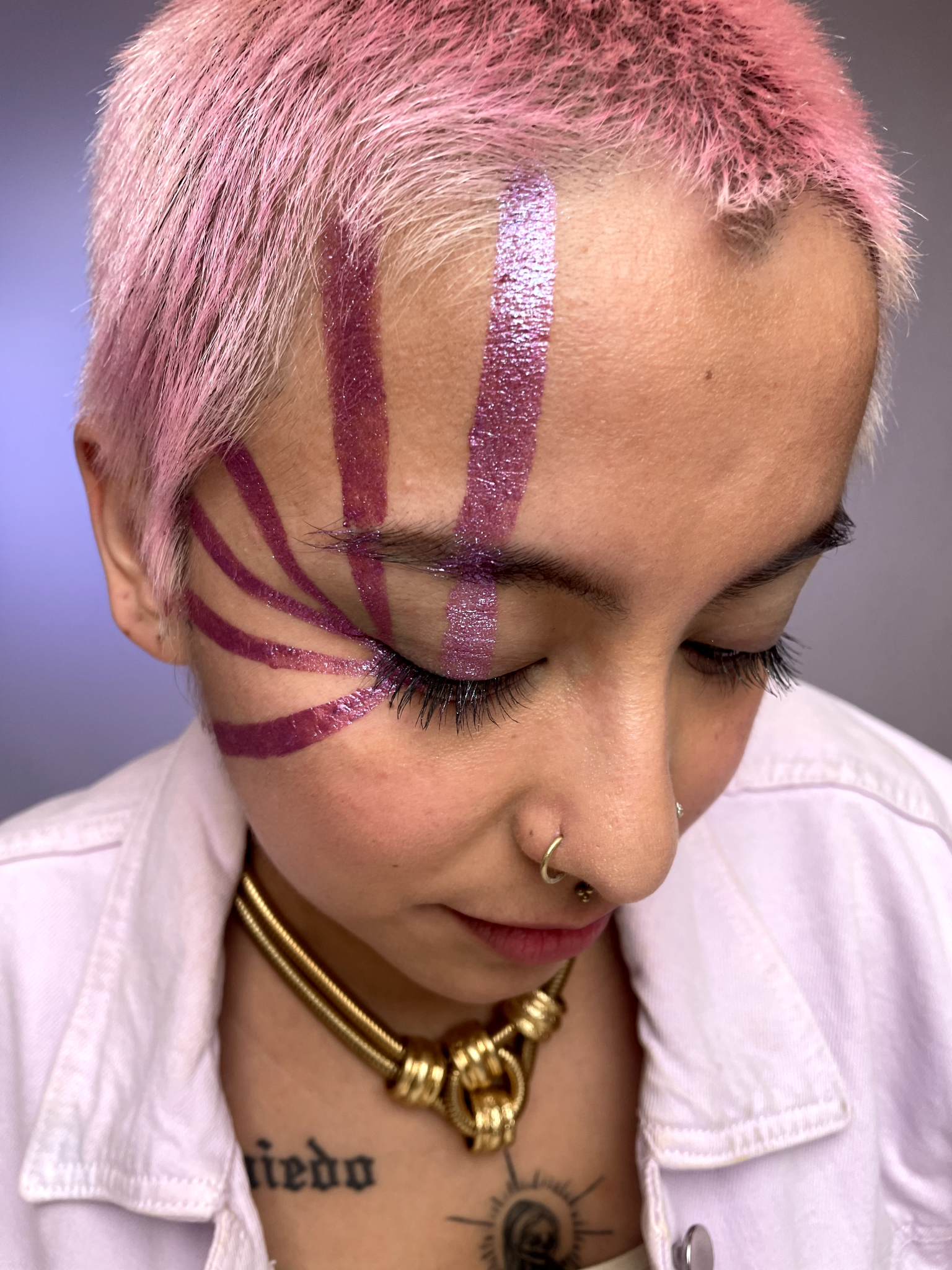 Model with medium skin wearing glabra in vertical stripes down the right side of their face. Applied using humanoid tape.