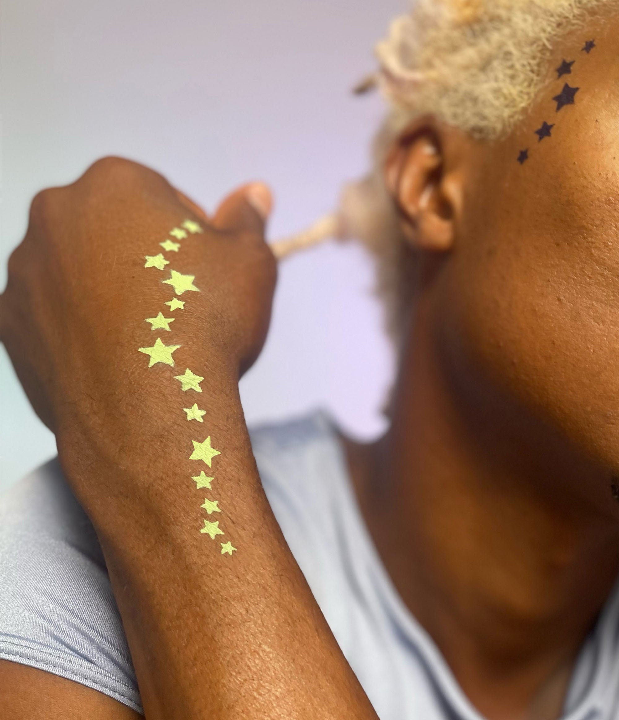 Model with dark skin wearing a star pattern along inner left wrist and hand in Sagebrush.