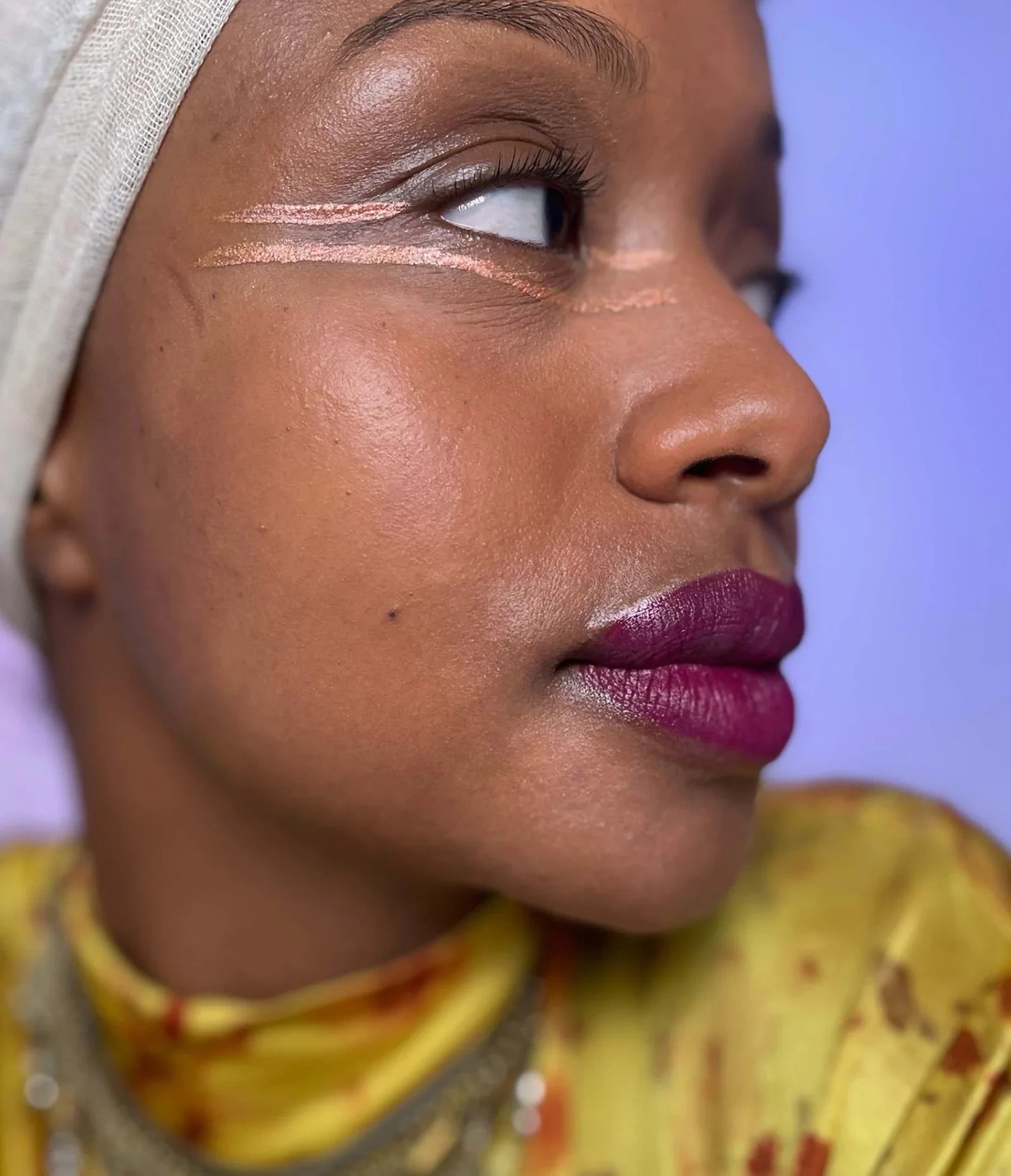 var:eventide | close-up of model wearing humanoid eventide deepdive pigment as bronze metallic eye lines with crimson shimmer